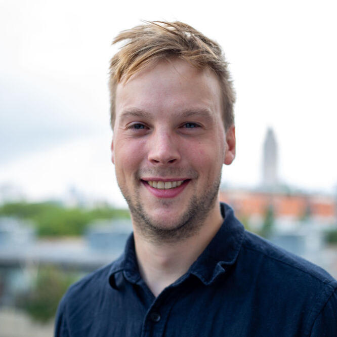 A portrait photo of Tim with blonde hair and blue shirt, smiling
